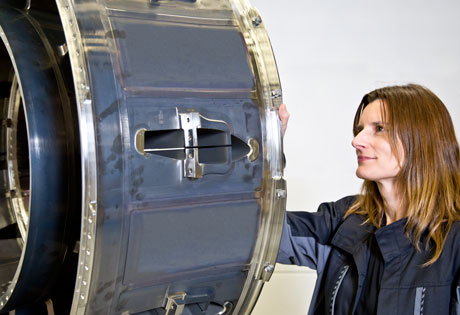 Bilden visar en av de detaljer, en Aft Rotating Frame, som GKN Aerospace i Trollhättan har levererat. Till höger står Lisa Falk, en av de som arbetat i projektet.